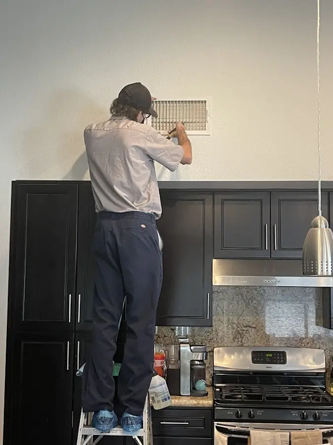 Technician inspecting an air vent during HVAC service in North Reading